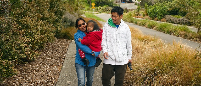 Young immigrant family walking in a green suburb