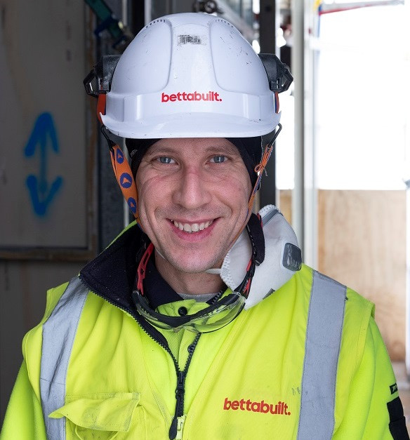 A migrant construction worker wearing safety helmet and vest