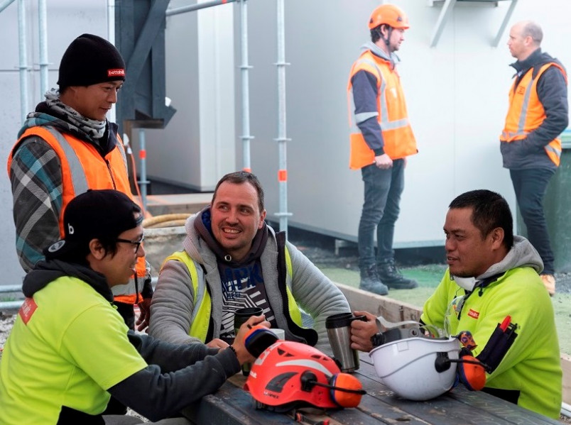 Migrant construction workers chatting around a table during a break