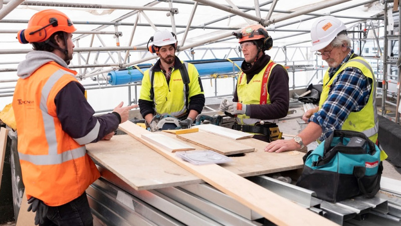 3 carpenters around a work bench talking to site manager