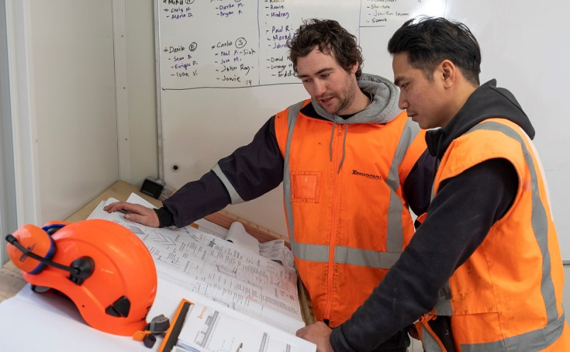 Project manager and migrant worker discussing building plans