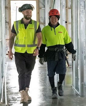 Migrant construction worker walking down a partially built corridor with his supervisor