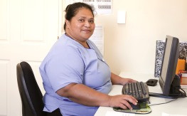 Nurse in blue uniform working at computer desk and smiling