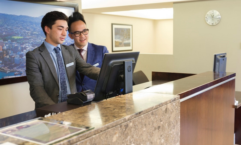 Hotel desk staff discussing bookings on the computer screen