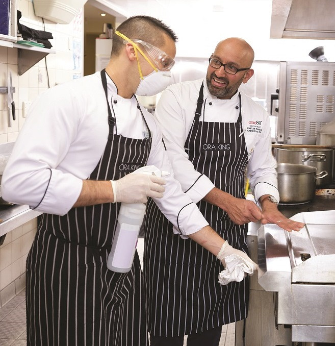 Chef and a kitchen worker wearing face mask, goggles and gloves