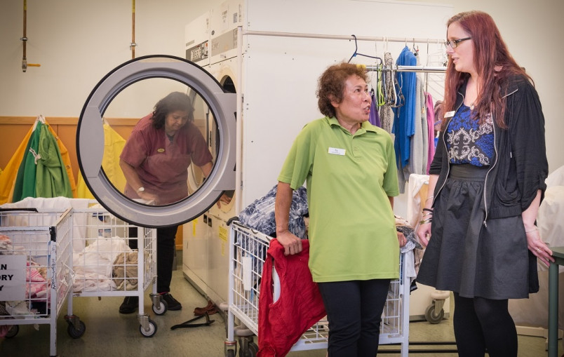 Two aged care village workers in laundry - one talking to her boss