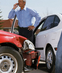 Man on cellphone beside a car involved in an accident