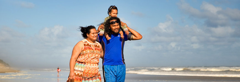 A woman walking with a man carrying a child on his shoulder