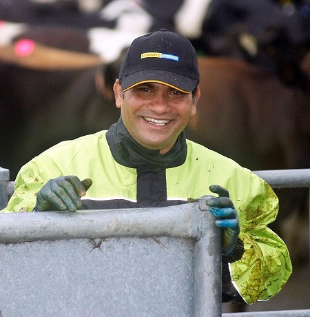 Smiling migrant worker in cow shed