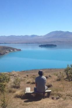 Person sitting on a bench looking at a lake