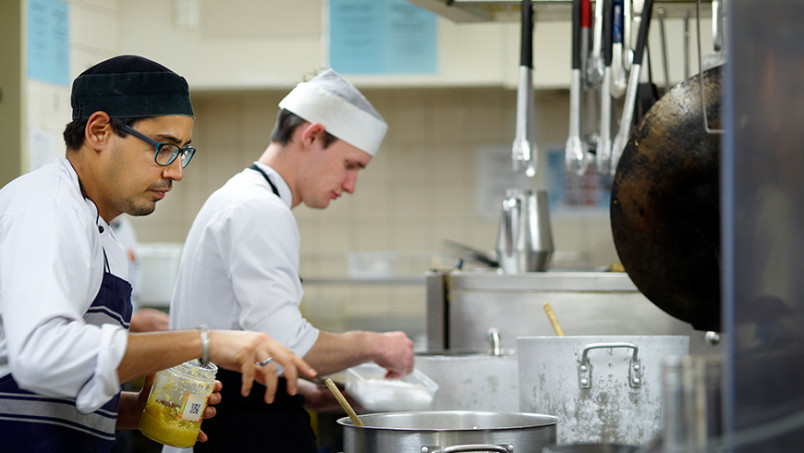 Migrant chefs in kitchen preparing food