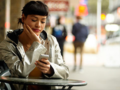 Migrant checking phone while sitting at table on footpath