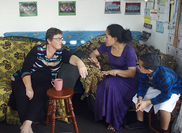 Two friends talking on a couch. A young son is listening